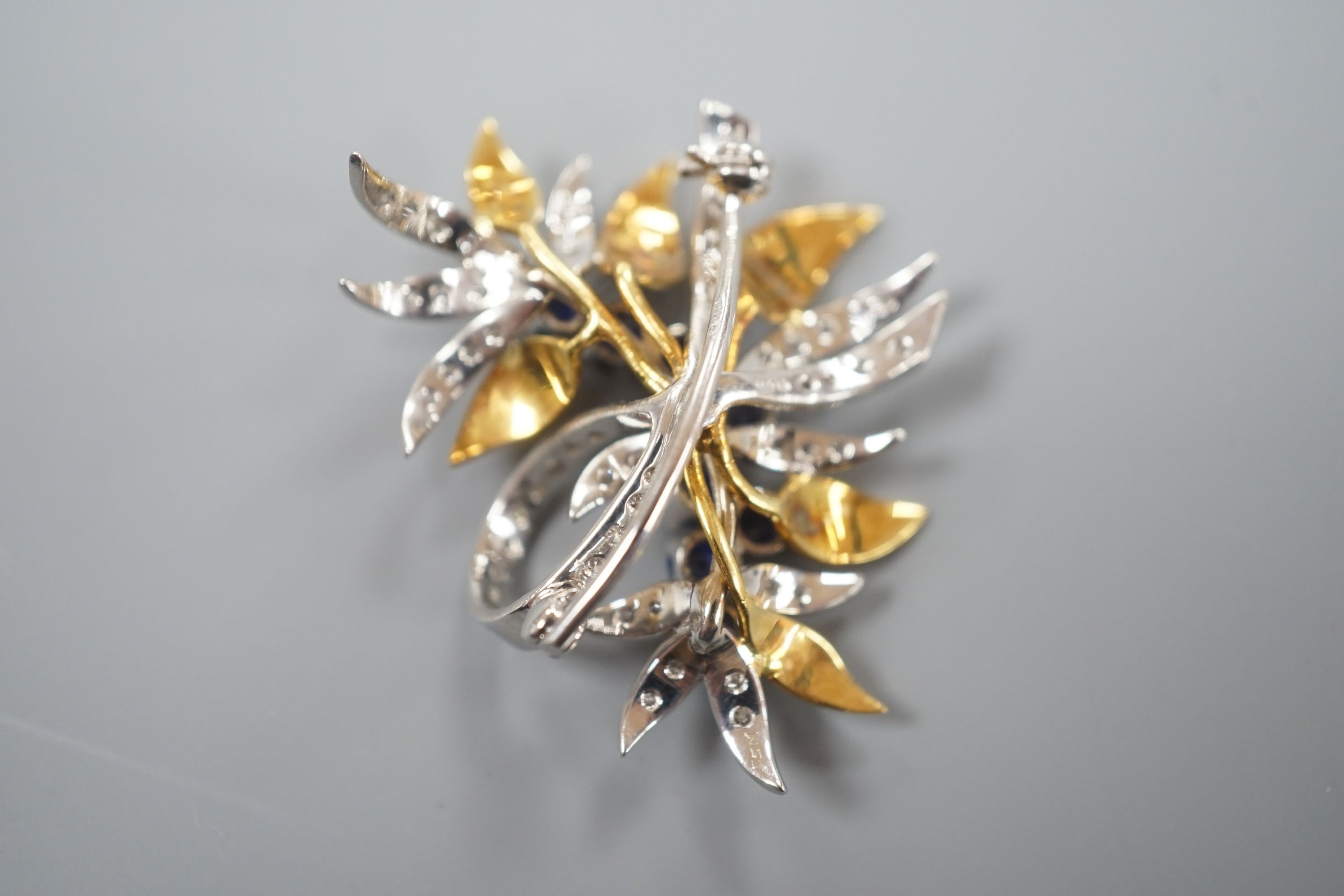 A modern 18ct two colour gold, sapphire and diamond set floral spray brooch, by Cropp & Farr, 38mm, gross weight 11.9 grams.